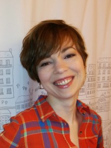 Woman wearing a plaid shirt. She has a long pixie haircut shown from the front.